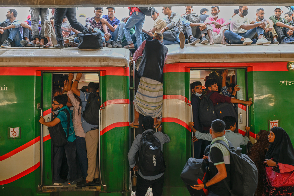 Homebound travelers scramble to board a train at Kamalapur Railway Station, joining the massive annual exodus to celebrate Eid al-Fitr, in Dhaka, Bangladesh, Wednesday, March 18, 2026. (AP Photo/Mahmud Hossain Opu)