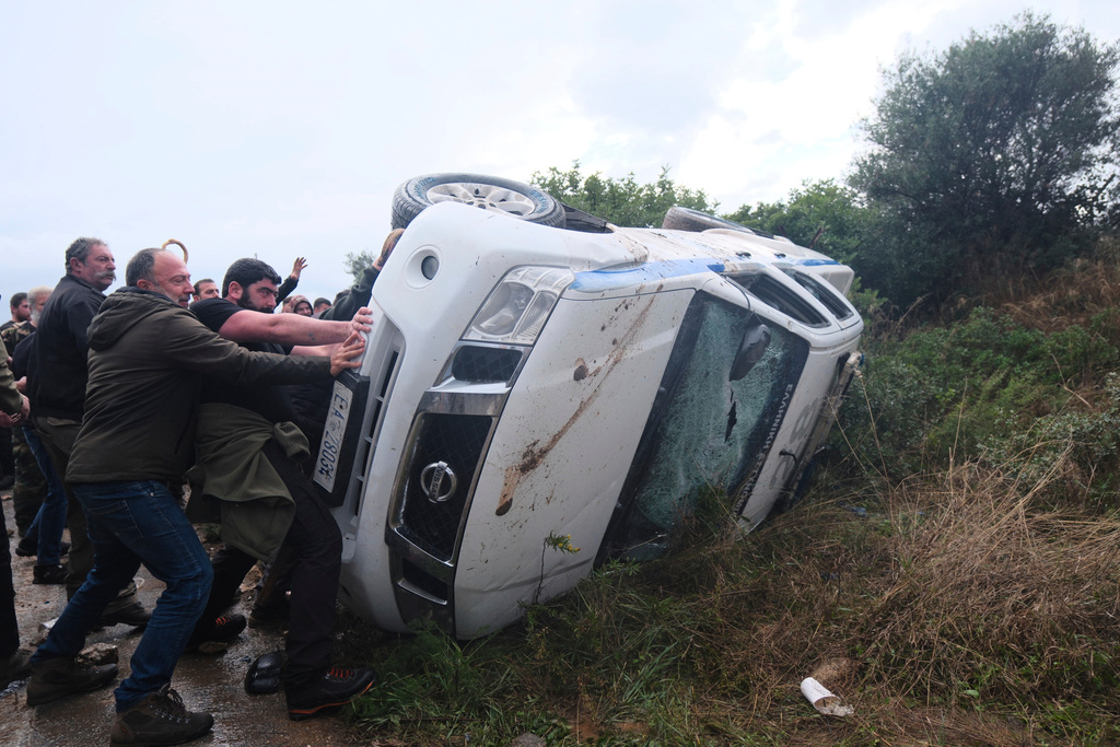 Farmers overturn a police vehicle during clashes with officers blocking their march to Chania's airport on Crete, Greece, Monday, Dec. 8, 2025, amid protests over delayed EU farm subsidies. (AP Photo/Giannis Angelakis)