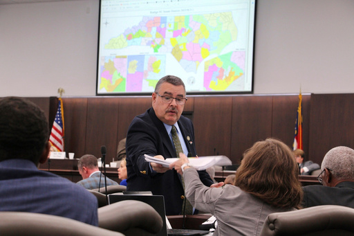 FILE - A sergeant-at-arms in the North Carolina state Senate passes out copies of a map proposal for new state Senate districts during a committee hearing at the Legislative Office Building in Raleigh, N.C., Oct. 19, 2023. (AP Photo/Hannah Schoenbaum, File) FILE - A sergeant-at-arms in the North Carolina state Senate passes out copies of a map proposal for new state Senate districts during a committee hearing at the Legislative Office Building in Raleigh, N.C., Oct. 19, 2023. (AP Photo/Hannah Schoenbaum, File)