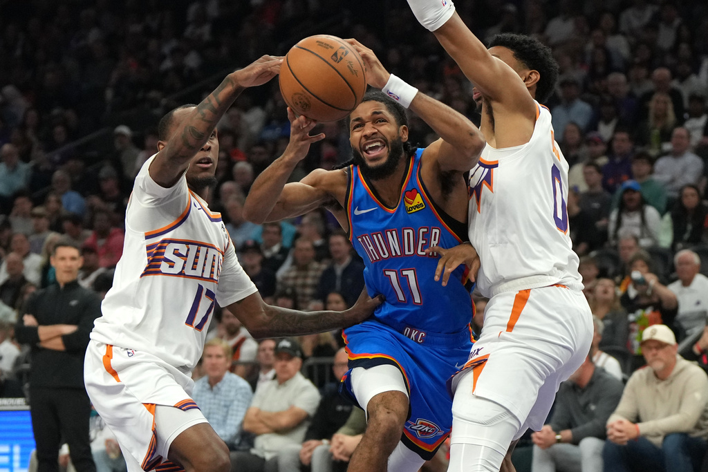 Oklahoma City Thunder guard Isaiah Joe drives between Phoenix Suns guard Amir Coffey (17) and forward Ryan Dunn during the first half of an NBA basketball game, Wednesday, Feb. 11, 2026, in Phoenix. (AP Photo/Rick Scuteri)