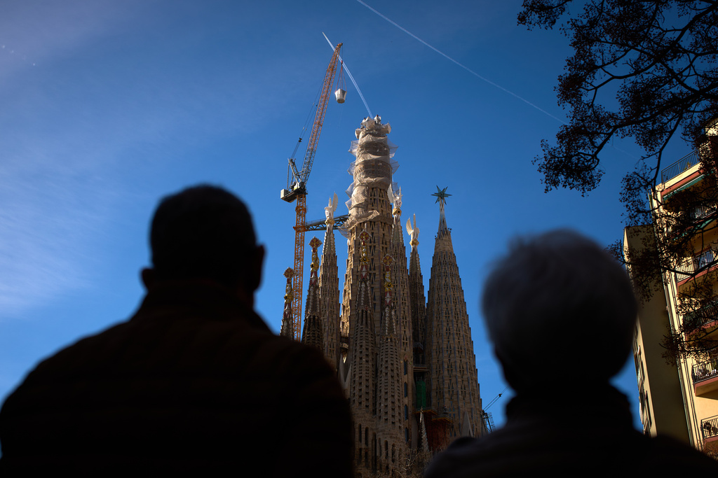 People watch as a crane lifts the upper arm of the cross onto the Tower of Jesus Christ at the Sagrada Familia in Barcelona, Spain, Friday, Feb. 20, 2026, reaching the basilica's maximum height of 172.5 meters (566 feet). (AP Photo/Emilio Morenatti)