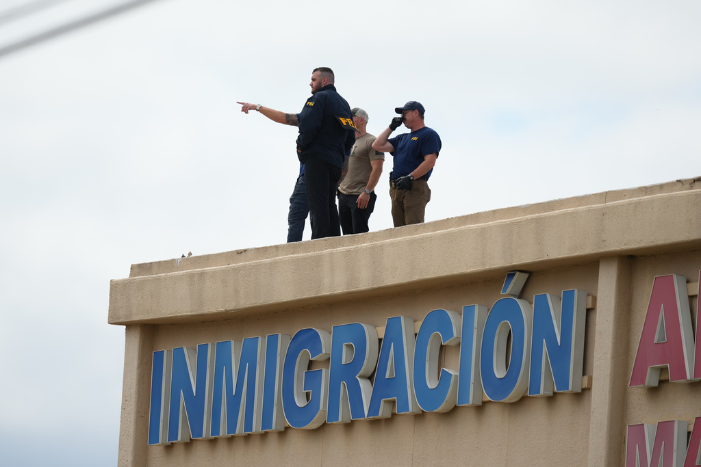 Law enforcement agents look around the roof of a building near the scene of a shooting at a U.S. Immigration and Customs Enforcement office in Dallas on Wednesday, Sept. 24, 2025. (AP Photo/Julio Cortez)