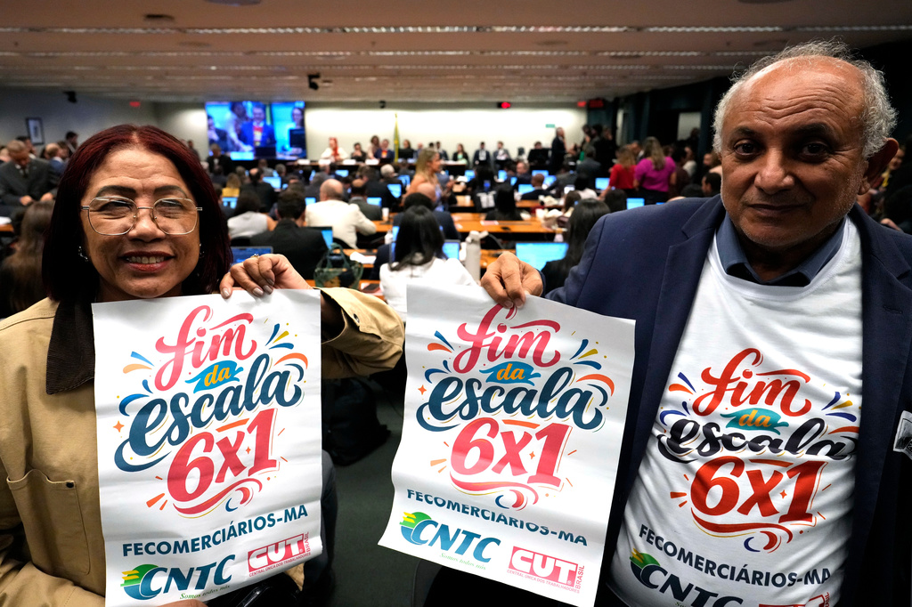 Labor union representatives hold signs calling for the end of Brazil's six-day workweek schedule during a special committee session analyzing the proposal at the Chamber of Deputies in Brasilia, Brazil, Wednesday, May 27, 2026. (AP Photo/Eraldo Peres)