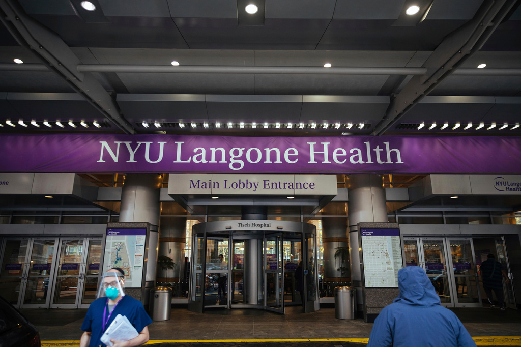 FILE - Health care workers walk in and out of the entrance at NYU-Langone Hospital on Dec. 14, 2020, in New York. (AP Photo/Kevin Hagen, File)