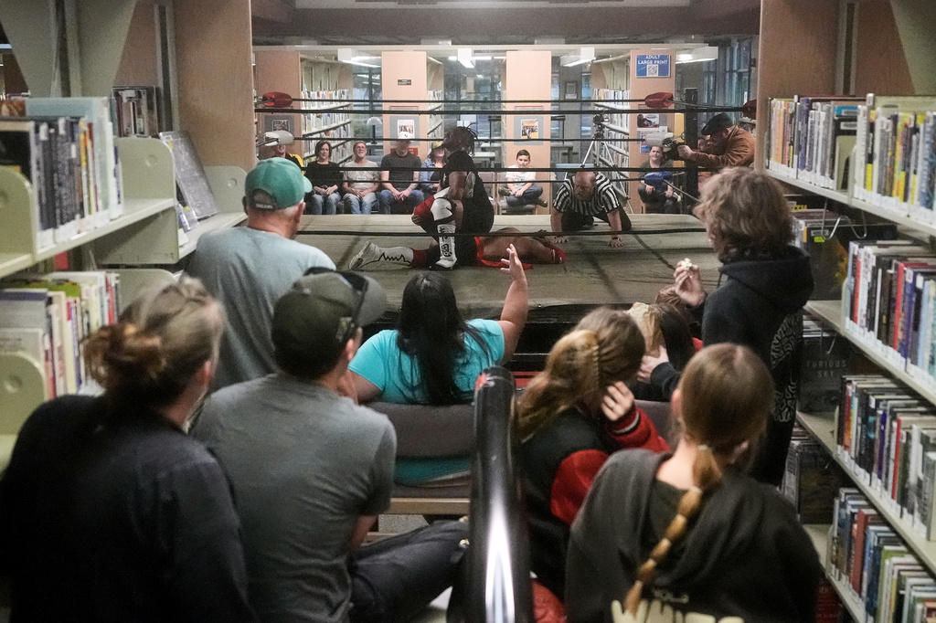 Fans watch as wrestler Hitman Wayne, middle top, applies a hold to Rufio Banderas during their match at a Lucha Libro pro wrestling event at Benicia Public Library Saturday, May 2, 2026, in Benicia, Calif. (AP Photo/Jeff Chiu)