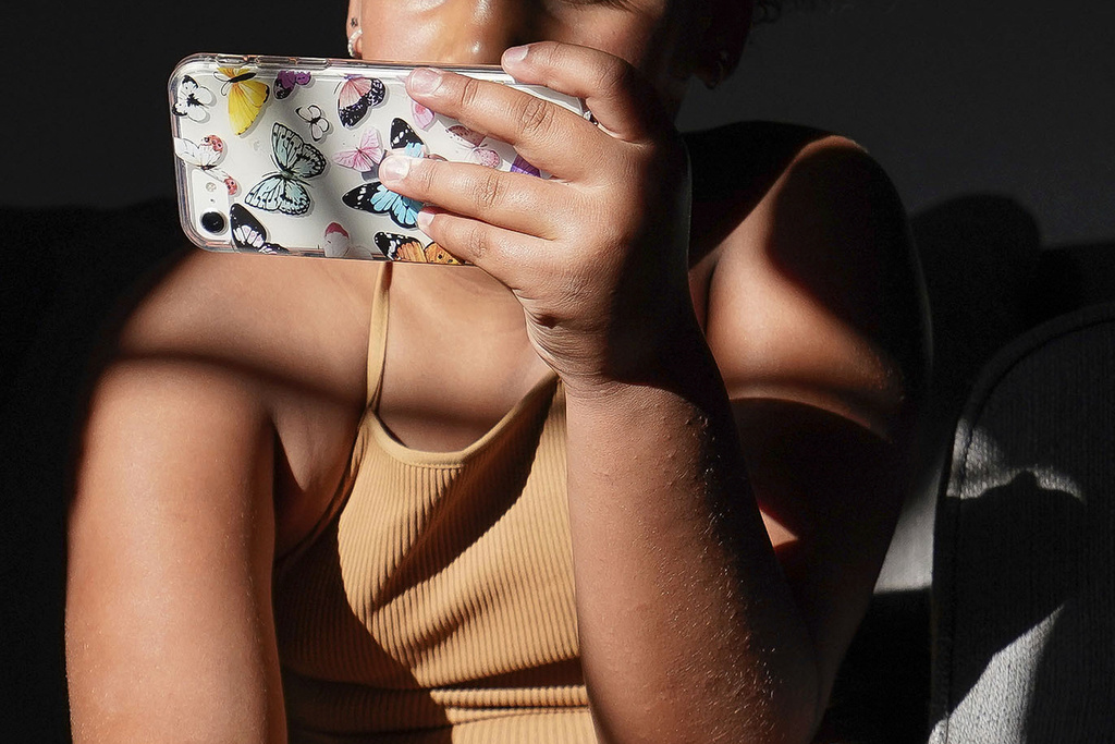 A girl uses her smartphone at home in Arizona on Friday, June 16, 2023. (AP Photo/Darryl Webb)