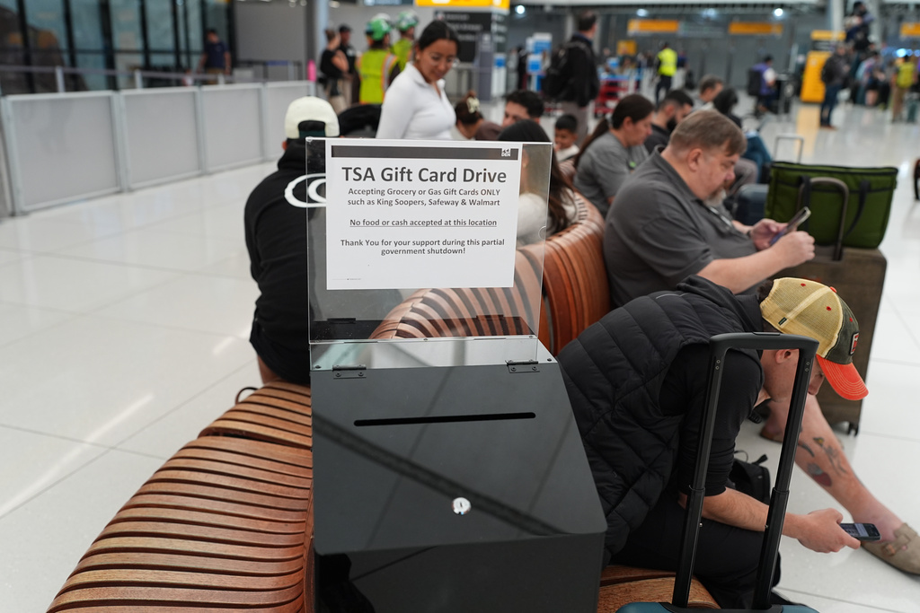 A collection box for gift card donations for TSA workers who have gone unpaid for several weeks, sits near travellers in the main terminal of Denver International Airport Friday, March 20, 2026, in Denver. (AP Photo/David Zalubowski)