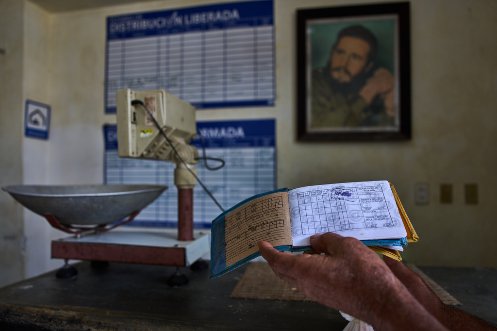 A man shows his ration book known as a "libreta," backdropped by a framed image of Fidel Castro, at a state-run bodega in Havana, Cuba, Saturday, May 2, 2026. (AP Photo/Ramon Espinosa)