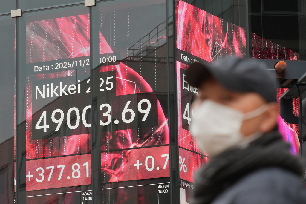 A person stands in front of an electronic stock board showing Japan's Nikkei index at a securities firm Tuesday, Nov. 25, 2025, in Tokyo. (AP Photo/Eugene Hoshiko)
