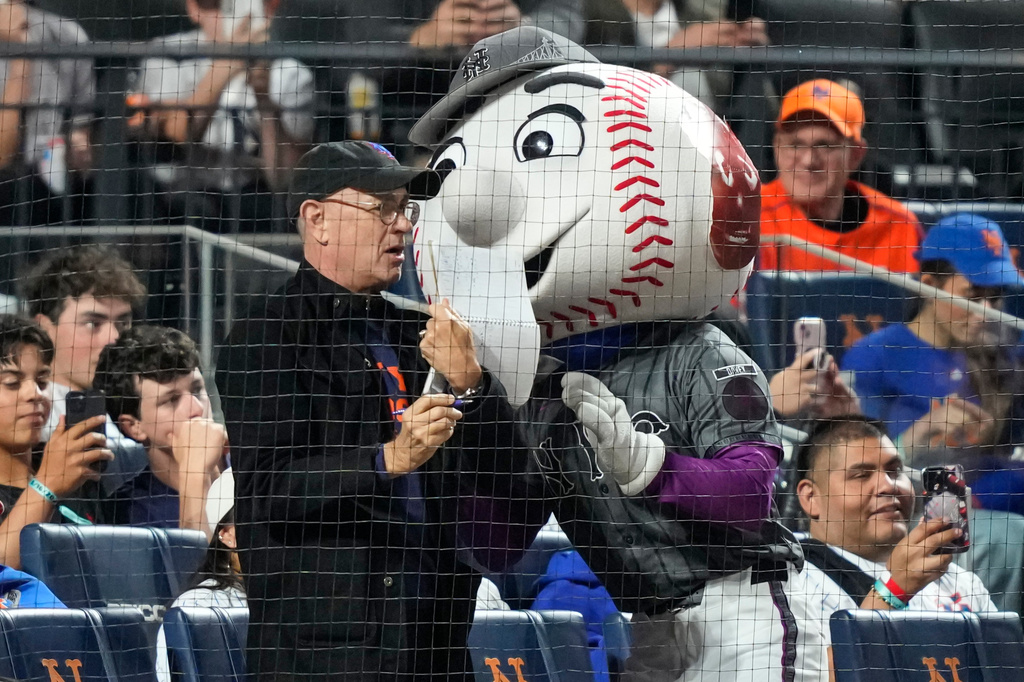 Actor/filmmaker Tom Hanks, center left, stands with Mr. Met, center right, during the sixth inning of a baseball game between the New York Mets and the New York Yankees, Saturday, May 16, 2026, in New York. (AP Photo/Yuki Iwamura)