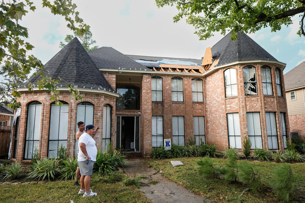 Jose Rosas, left, and Guillermo Vargas survey damage to Vargas' home as they clean up storm damage in the Memorial Northwest subdivision in Spring, Texas, Monday, Nov. 24, 2025. (Brett Coomer/Houston Chronicle via AP)