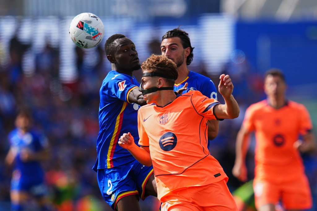 Barcelona's Fermin Lopez, front, is challenged by Getafe's Djene Dakonam during the Spanish La Liga soccer match between Getafe and Barcelona in Getafe, Spain, Saturday, April 25, 2026. (AP Photo/Manu Fernandez)