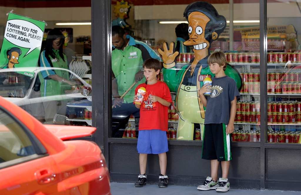 FILE - Children appear next to a window display featuring "The Simpsons" character Apu Nahasapeemapetilon Jr. outside a 7-Eleven Kwik-E-Mart in Burbank, Calif., on July 2, 2007. (AP Photo/Damian Dovarganes, File)