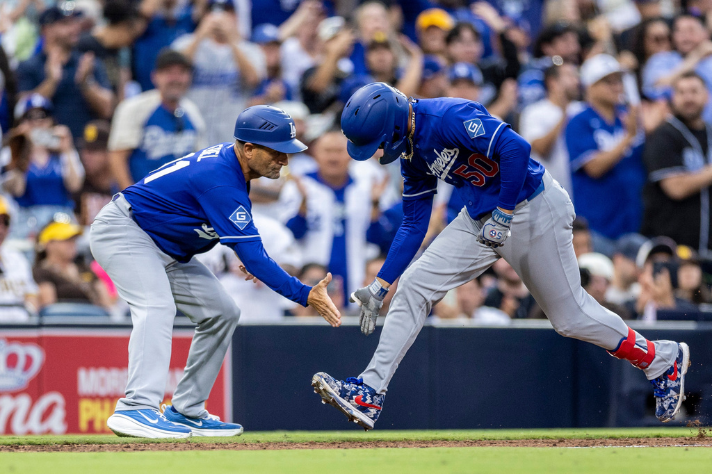 Los Angeles Dodgers' Mookie Betts (50) gets a hand from third base coach Dino Ebel, left, after hitting a three-run home run in the sixth inning of a baseball game against the San Diego Padres, Saturday, June 27, 2026, in San Diego. (AP Photo/Tony Ding)