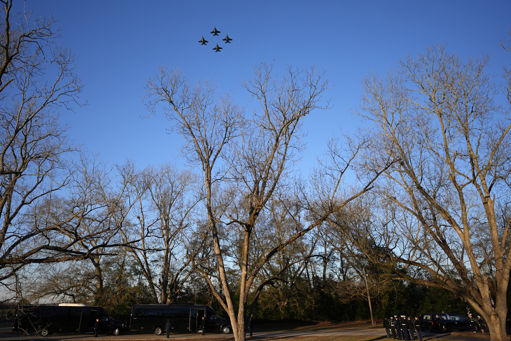 U.S. Navy F/A-18 Super Hornets perform a fly-over as as the casket of former President Jimmy Carter, bottom right, arrives at Maranatha Baptist Church for a funeral service, Thursday, Jan. 9, 2025, in Plains, Ga. (AP Photo/Mike Stewart)
