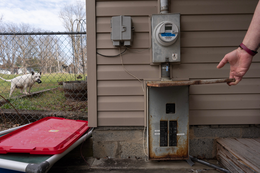 Ashley Nicole Dixon shows her electrical panel below the electric meter as one of her rescued dogs, Lola, holds a toy, at her home in Danese, W.Va., Saturday, March 21, 2026. (AP Photo/Carolyn Kaster)