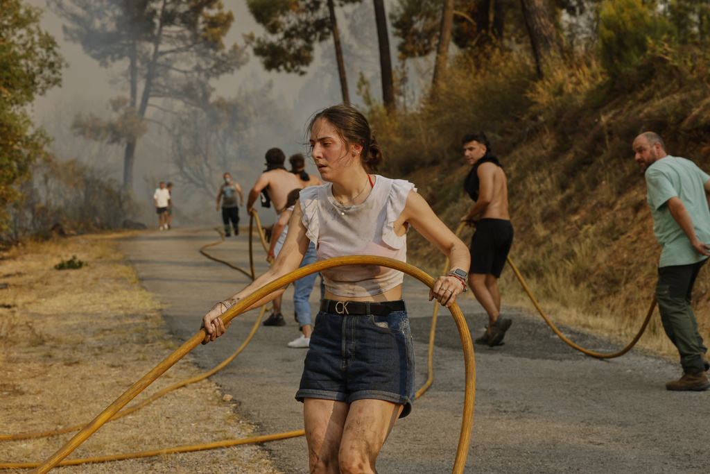 Local residents and volunteers try to put out a wildfire in Larouco, northwestern Spain, Wednesday, Aug. 13, 2025. (AP Photo/Lalo R. Villar)