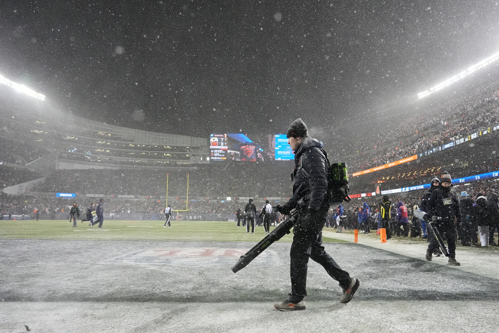 Grounds crew members glow snow off the field at Soldier Field during the first half of an NFL football divisional playoff game between the Chicago Bears and the Los Angeles Rams Sunday, Jan. 18, 2026, in Chicago. (AP Photo/Nam Y. Huh)