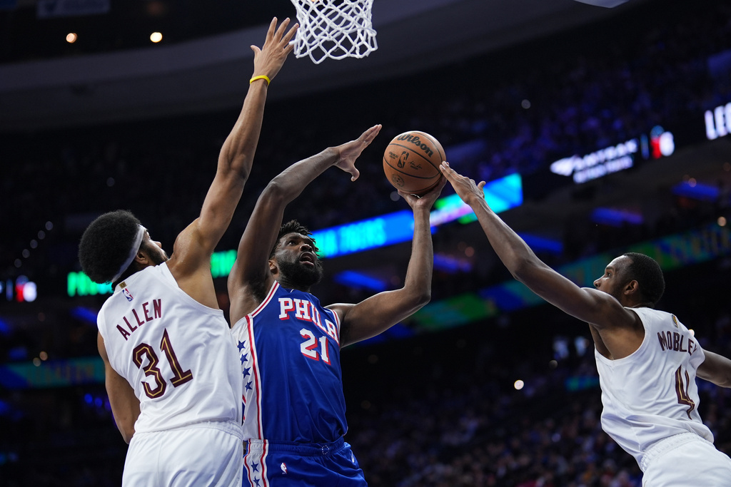 Philadelphia 76ers' Joel Embiid, center, goes up for a shot between Cleveland Cavaliers' Jarrett Allen, left, and Evan Mobley during the first half of an NBA basketball game Wednesday, Jan. 14, 2026, in Philadelphia. (AP Photo/Matt Slocum)