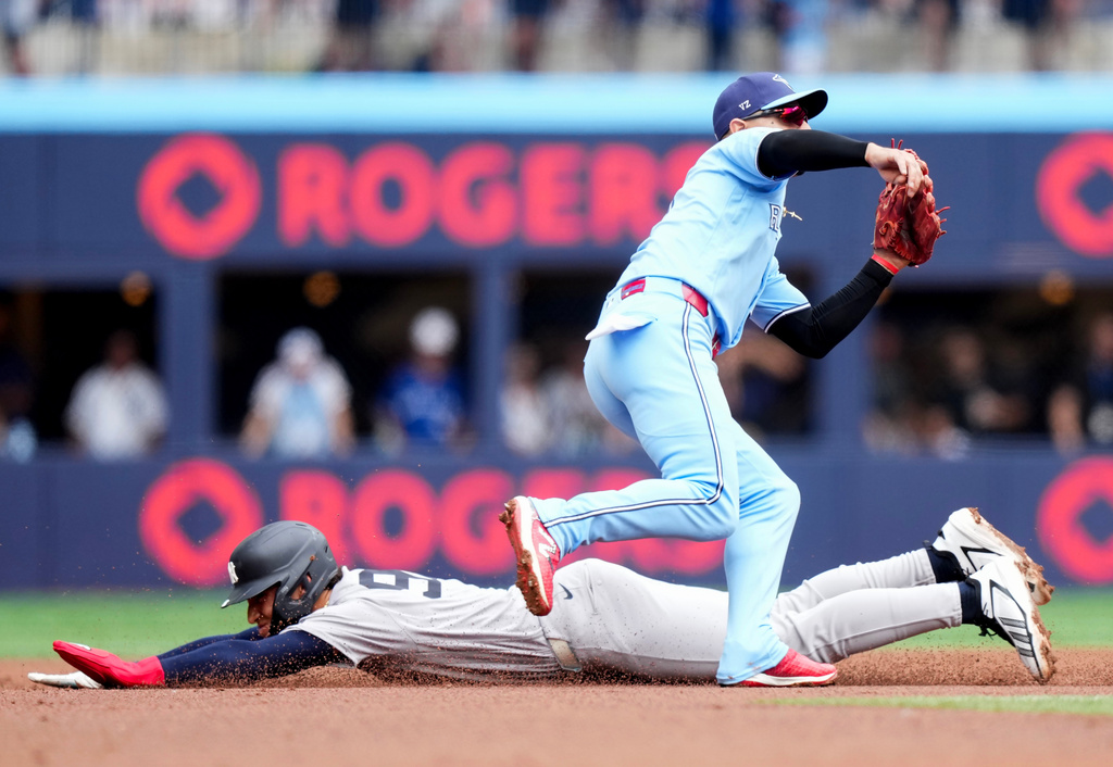 New York Yankees' George Lombard Jr., bottom, steals second base past Toronto Blue Jays shortstop Andrés Giménez, top, during the second inning of a baseball game in Toronto, Sunday, Aug. 16, 2026. (Nathan Denette/The Canadian Press via AP)