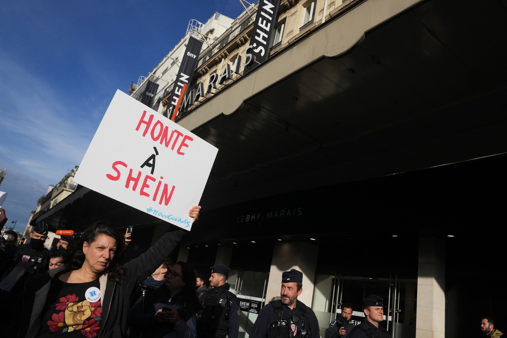 A demonstrator holds a poster reading "Shame on Shein" outside the BHV department store where fast fashion powerhouse Shein's first permanent store is set to open, Wednesday, Nov. 5, 2025 in Paris. (AP Photo/Thibault Camus)