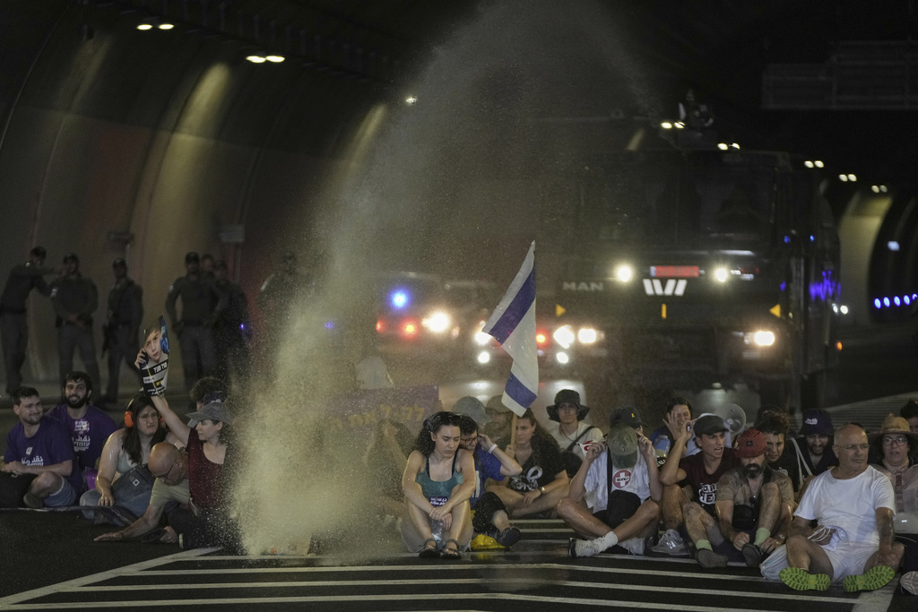 Police uses water canon to disperse demonstrators blocking a road during a protest demanding the immediate release of hostages held by Hamas and calling for the Israeli government to reverse its decision to take over Gaza City and other areas in the Gaza Strip, in Jerusalem, Sunday, Aug. 17, 2025. (AP Photo/Mahmoud Illean)