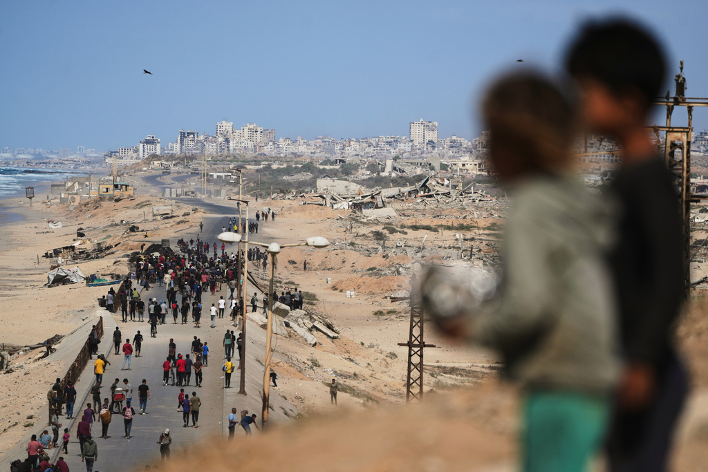 Displaced Palestinians gather on the coastal road near Wadi Gaza after the announcement that Israel and Hamas had agreed to the first phase of a peace plan to pause the fighting, as Israeli tanks block the road leading to Gaza City, in the central Gaza Strip, Thursday, Oct. 9, 2025. (AP Photo/Abdel Kareem Hana)