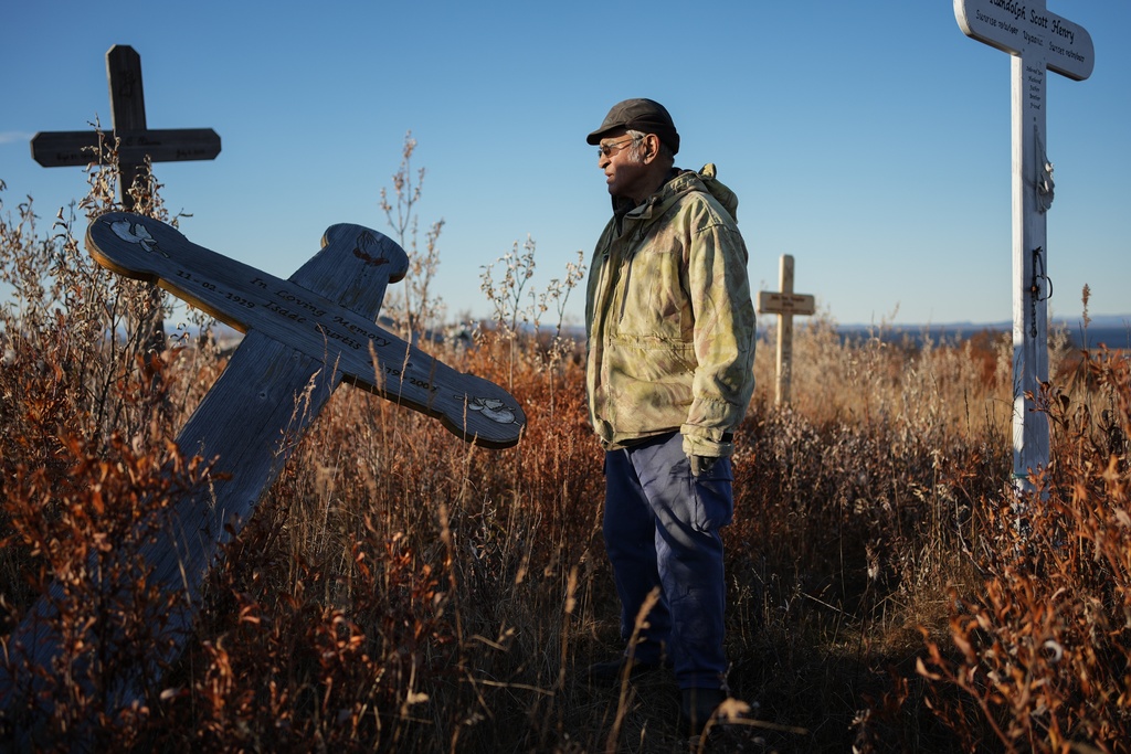 Roswell Schaeffer, an Inupiaq hunter and fisher, visits the cemetery where thawing permafrost has caused grave markers to tilt in Kotzebue, Alaska, Friday, Sept. 26, 2025. (AP Photo/Annika Hammerschlag)