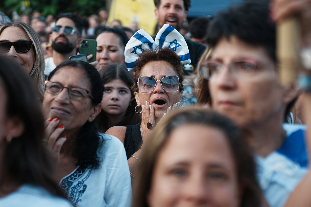 People react as they gather to watch a live broadcast of Israeli hostages released from Gaza at a plaza known as hostages square in Tel Aviv, Israel, Monday, Oct. 13, 2025. The release took place as part of a cease-fire agreement between Israel and Hamas. (AP Photo/Emilio Morenatti)