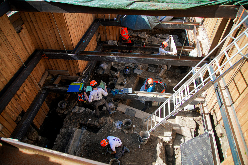 Archaeological workers wearing hard hats dig 4 meters (13 feet) underground during excavations outside Notre-Dame Cathedral in Paris, Monday, June 1, 2026. (AP Photo/Nicolas Garriga)