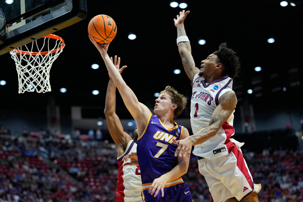 Northern Iowa guard Ben Schwieger, center, shoots as St. John's forward Zuby Ejiofor (24) and forward Dillon Mitchell, right, defend during the first half in the first round of the NCAA college basketball tournament Friday, March 20, 2026, in San Diego. (AP Photo/Mark J. Terrill)