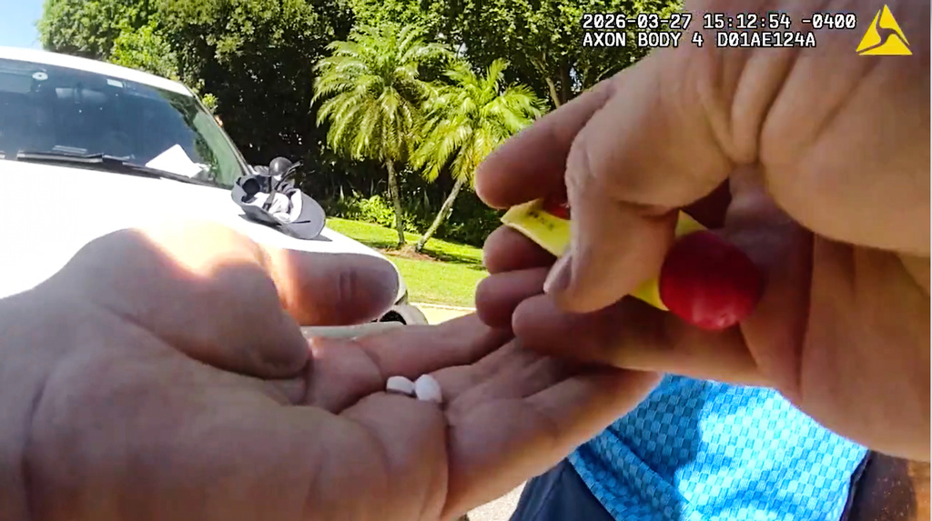 In this image taken from police body camera video released by the Martin County, Fla., Sheriff's Office, sheriff's deputies holds two pills from a search of golfer Tiger Woods' pants following a car crash in Jupiter Island, Fla., Friday, March 27, 2026. (Martin County Sheriff's Department via AP)
