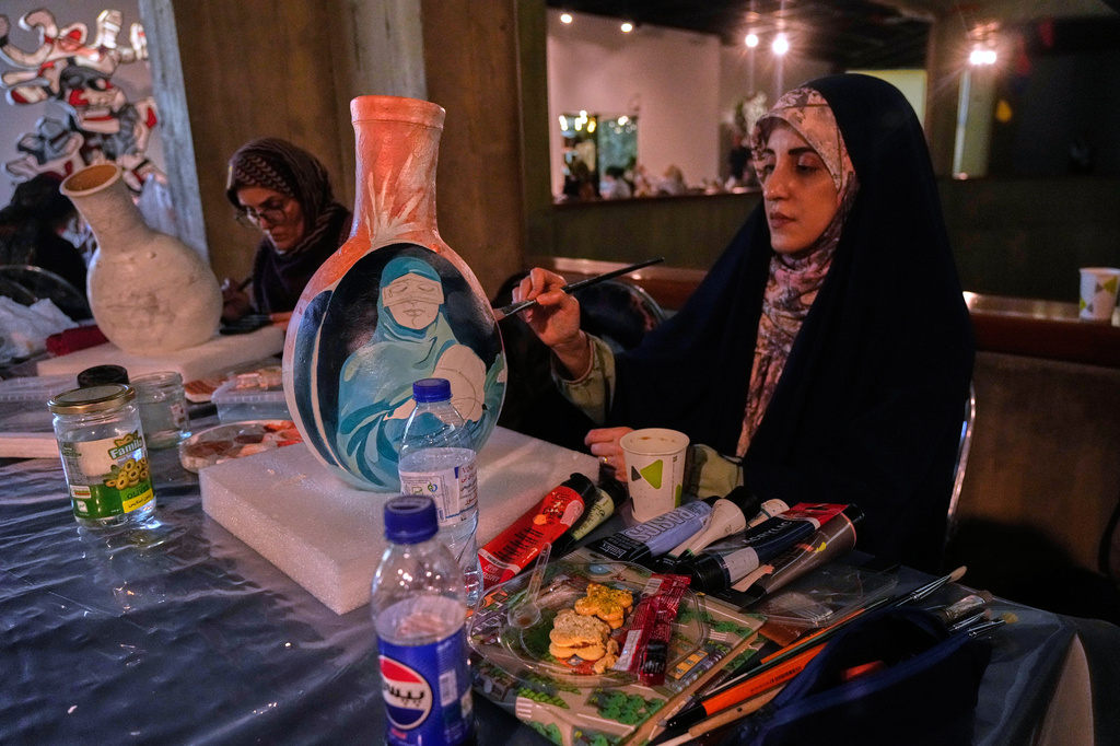Artist Sahar Farhadravesh, works on a ceramic jar inspired by schoolchildren killed in a Feb. 28, 2026 strike on a school in the southern Iranian city of Minab that was likely caused by U.S. airstrikes, during "A Sign on Minab," an event honoring their memory, at the Museum of Contemporary Art in Tehran, Iran, Sunday, June 14, 2026. (AP Photo/Vahid Salemi)
