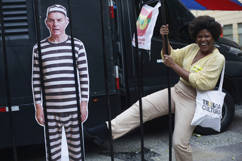 An opponent kicks at a cutout depicting Brazil's former President Jair Bolsonaro in prison garb, as she celebrates a day after the Supreme Court sentenced him to more than 27 years in prison for attempting a coup to remain in office despite his 2022 electoral defeat, in Rio de Janeiro, Friday, Sept. 12, 2025. (AP Photo/Bruna Prado)