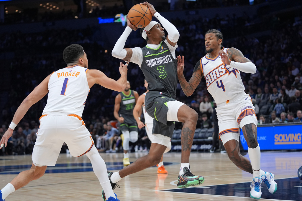 Minnesota Timberwolves forward Jaden McDaniels (3) works toward the basket as Phoenix Suns guards Devin Booker (1) and Jalen Green (4) defend during the first half of an NBA basketball game, Tuesday, March 17, 2026, in Minneapolis. (AP Photo/Abbie Parr)
