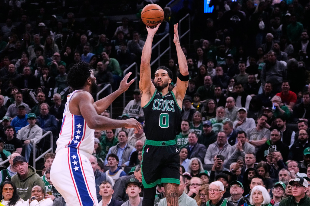 Boston Celtics forward Jayson Tatum (0) takes a 3-point shot over Philadelphia 76ers center Joel Embiid, left, during the first half of Game 5 of a first-round NBA playoffs basketball series, Tuesday, April 28, 2026, in Boston. (AP Photo/Charles Krupa)