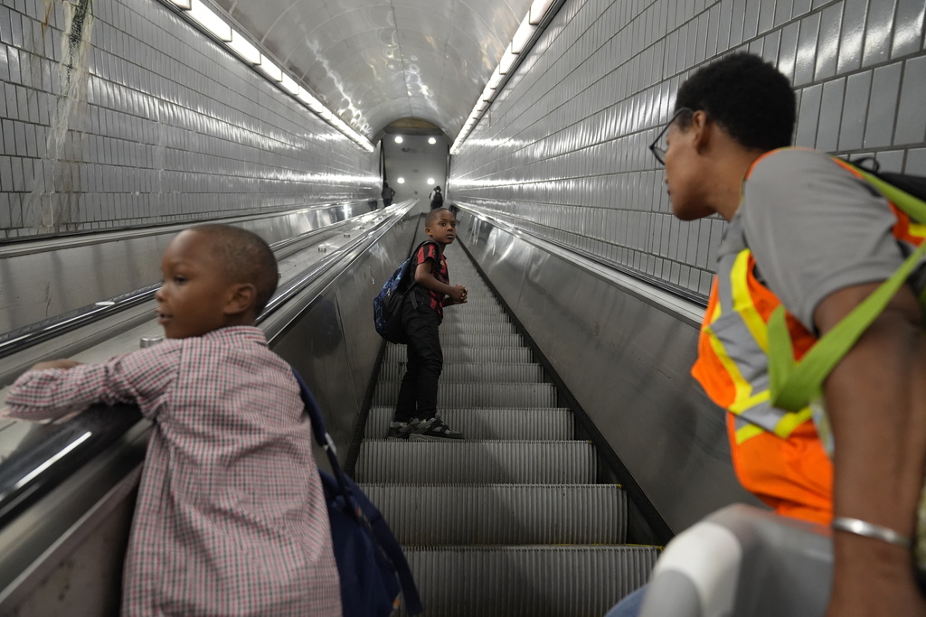 Sechita McNair, right, and sons Derrick McNair-White, 6, center, and Malachi McNair-Nesbitt, 6, left, ride an escalator to the train on June 11, 2025, in Atlanta. (AP Photo/Brynn Anderson)