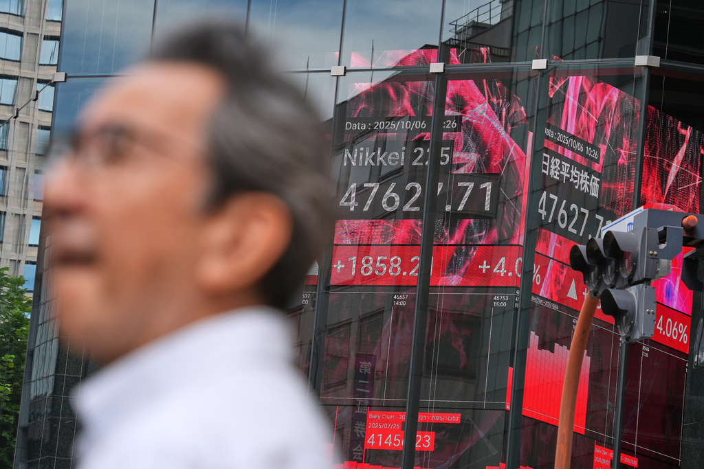 A person stand in front of an electronic stock board showing Japan's Nikkei index at a securities firm Monday, Oct. 6, 2025, in Tokyo. (AP Photo/Eugene Hoshiko)