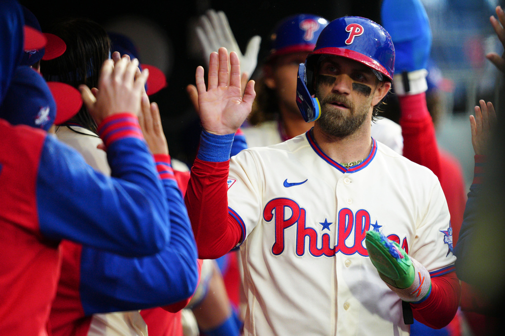Philadelphia Phillies' Bryce Harper, right, high-fives teammates after scoring on a single hit by Bryson Stott during the fourth inning of a baseball game against the Cleveland Guardians, Saturday, May 23, 2026, in Philadelphia. (AP Photo/Derik Hamilton)