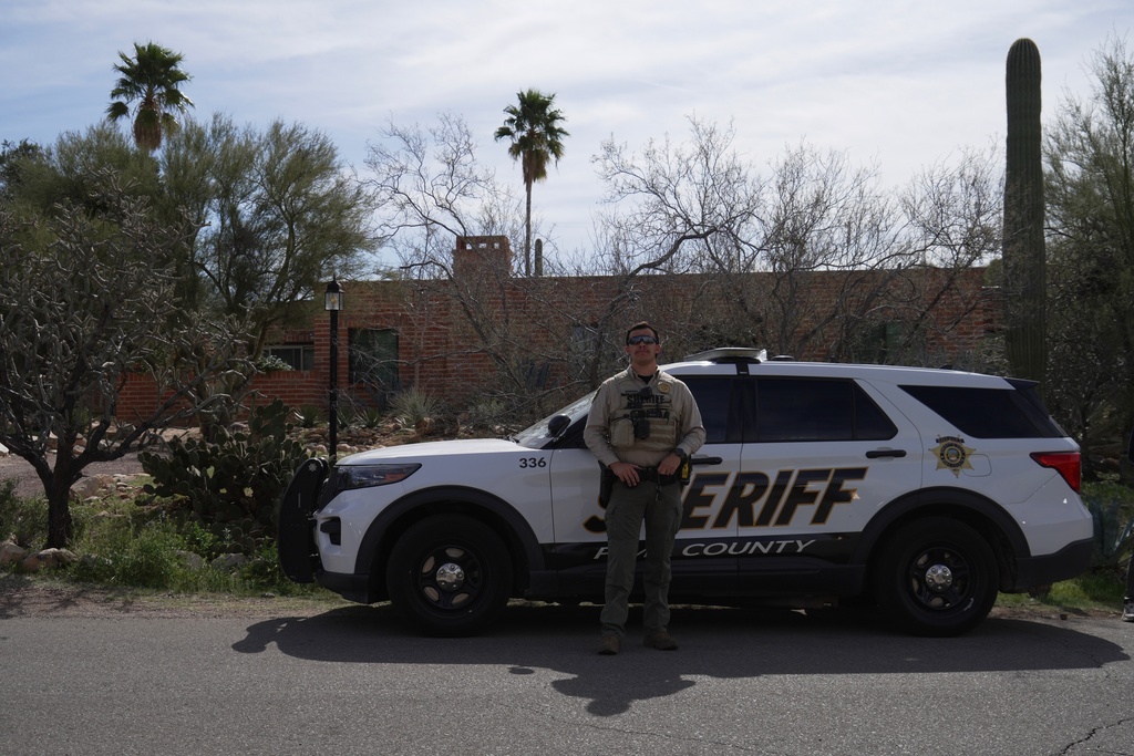 A Pima County Sheriff's Department member stands next to his vehicle in front of Nancy Guthrie's home Tuesday, Feb. 10, 2026 in Tucson, Ariz. (AP Photo/Ty ONeil)