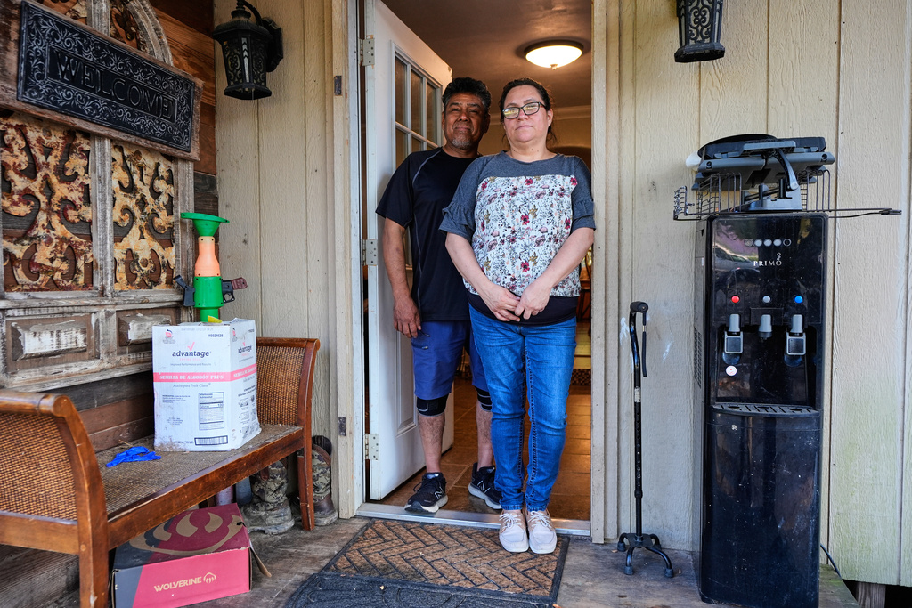 Celia Monreal and her husband Jorge, left, pose for a photo at her in the entry way of their home Wednesday, Oct. 8, 2025, in Tyler, Texas. (AP Photo/Tony Gutierrez)