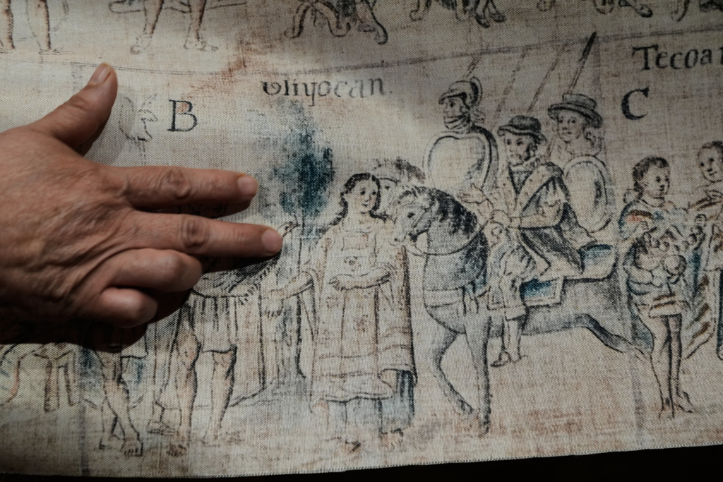 Areli Ortiz, technical deputy director of the National Institute of Anthropology and History, points to depictions on fabric of La Malinche and Hernan Cortes from a facsimile of part of the 16th century Tlaxcala Codex in Mexico City, Wednesday, Oct. 8, 2025. (AP Photo/Marco Ugarte)