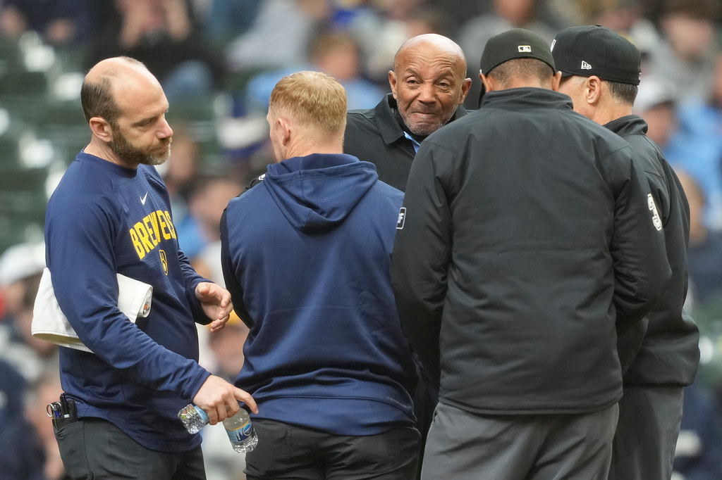 Umpire CB Bucknor, center, looks on after being hit by a foul ball during the second inning of a baseball game between the Milwaukee Brewers and the Tampa Bay Rays, Wednesday, April 1, 2026, in Milwaukee. Bucknor excited the game following the incident. (AP Photo/Kayla Wolf)