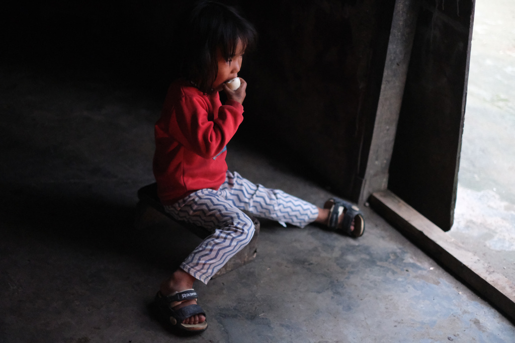 Azatina Murru, 3, eats an egg by the entrance of her home in Kohima, capital of the northeastern Indian state of Nagaland, Monday, July 6, 2026. (AP Photo/Yirmiyan Arthur)