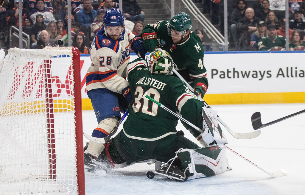 Minnesota Wild goalie Jesper Wallstedt (30) makes the save as Edmonton Oilers' Jack Roslovic (28) and Wild's Daemon Hunt (48) battle for the rebound during second period NHL action, in Edmonton on Saturday, Jan. 31, 2026. (Jason Franson/The Canadian Press via AP)