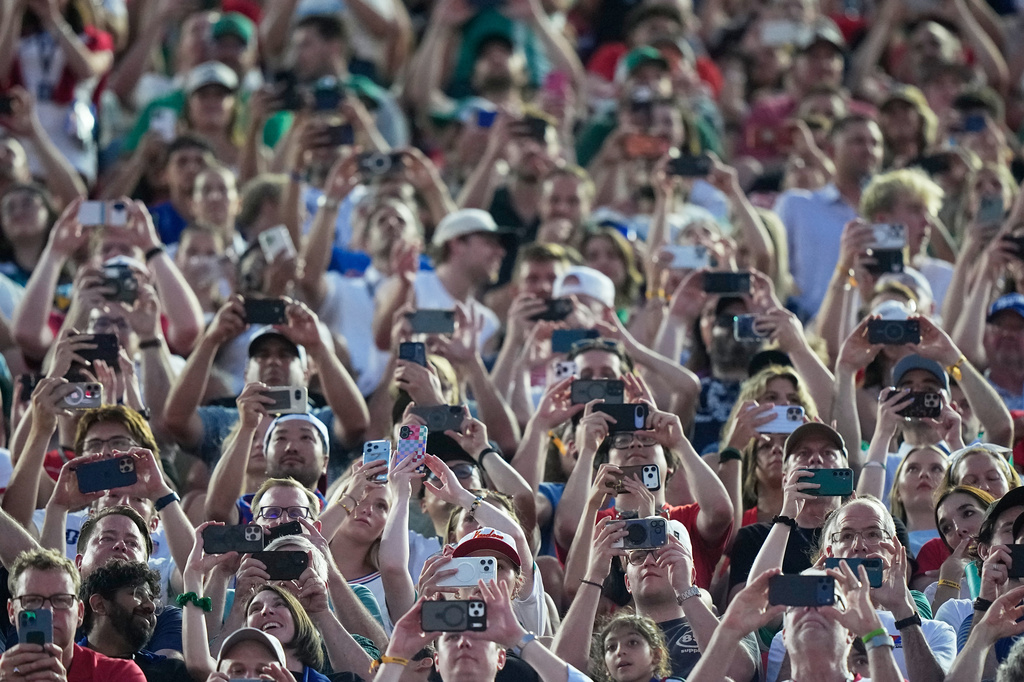 Fans hold their cell phones during the World Cup Group J soccer match between Algeria and Austria in Kansas City, Mo., Saturday, June 27, 2026. (AP Photo/Charlie Riedel)