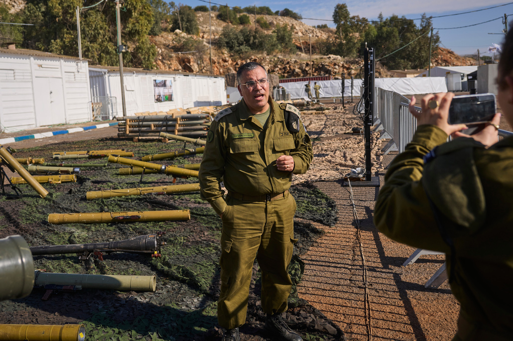 Avichay Adraee, the Israeli military’s Arabic language spokesman, stands beside weapons the army says were seized from Hezbollah in Lebanon, at an army base in northern Israel, Dec. 23, 2024. (AP Photo/Ohad Zwigenberg)