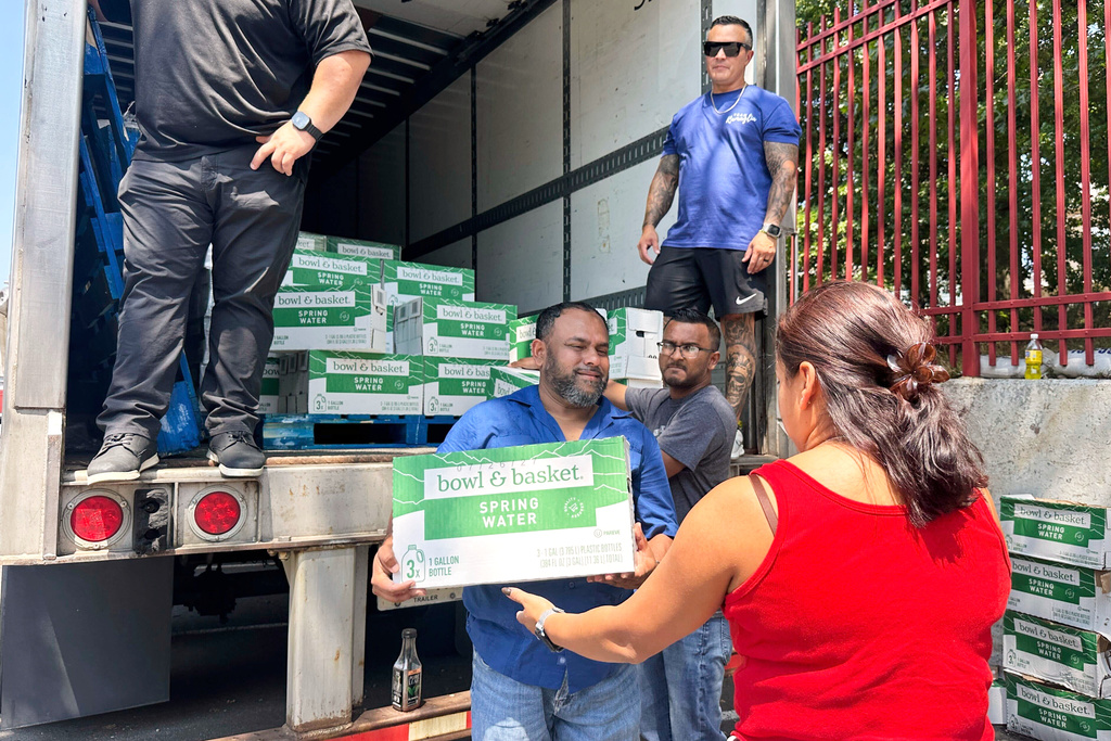 People, who were affected by a water main break that that led to reduced service to nearly 200,000 homes and businesses, pick up cases of bottled water at John F. Kennedy High School in Paterson, N.J., on Aug. 11, 2025. (AP Photo/Ted Shaffrey)