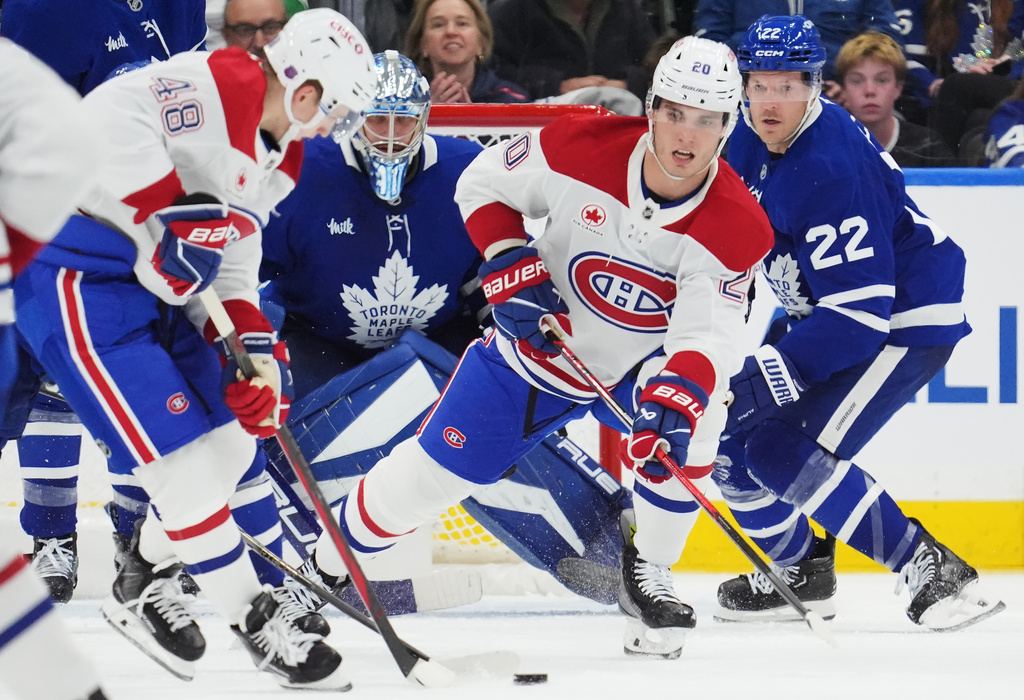 Montreal Canadiens' Lane Hutson (48) and Juraj Slafkovsky (20) work for the puck as Toronto Maple Leafs goaltender Anthony Stolarz (41) and Jake McCabe (22) look on during second period NHL hockey action in Toronto on Wednesday, Oct. 8, 2025. (Frank Gunn/The Canadian Press via AP)