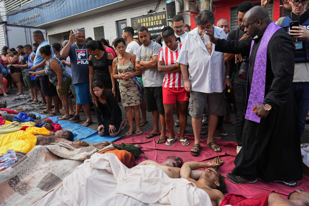 FILE - A priest blesses the bodies of people killed the day before during a police raid targeting the Comando Vermelho gang in the Complexo da Penha favela of Rio de Janeiro, Brazil, Wednesday, Oct. 29, 2025. (AP Photo/Silvia Izquierdo, File)